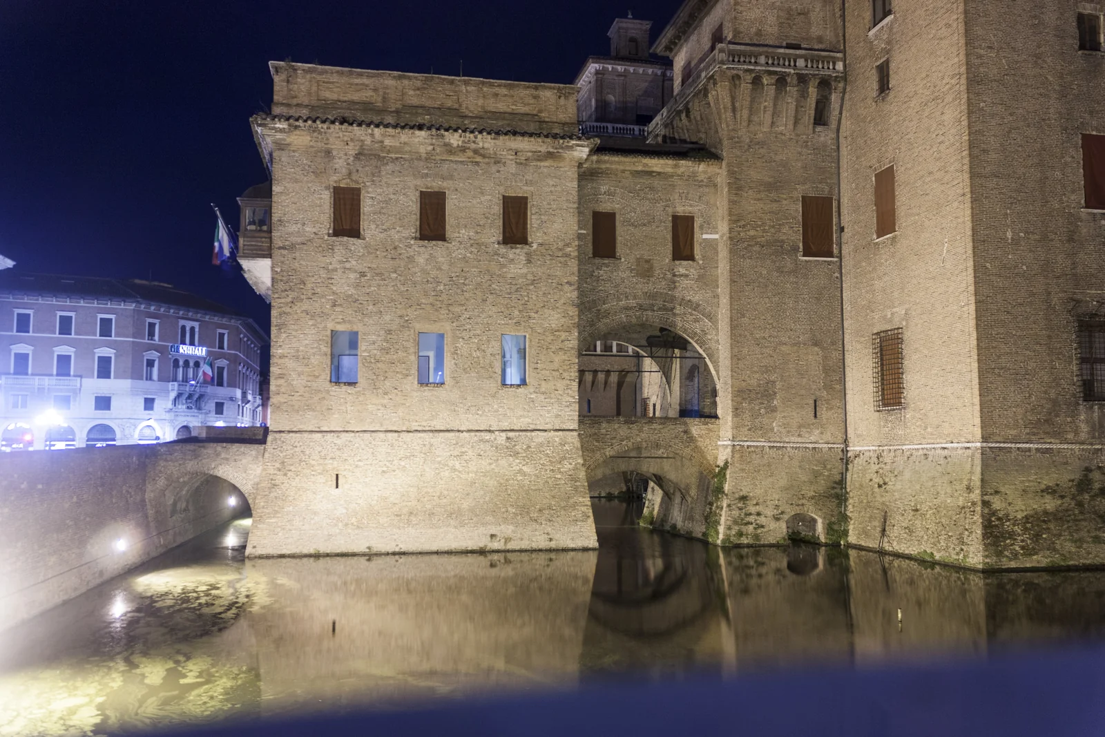 Torres del castillo de Ferrara iluminadas y reflejadas en el foso