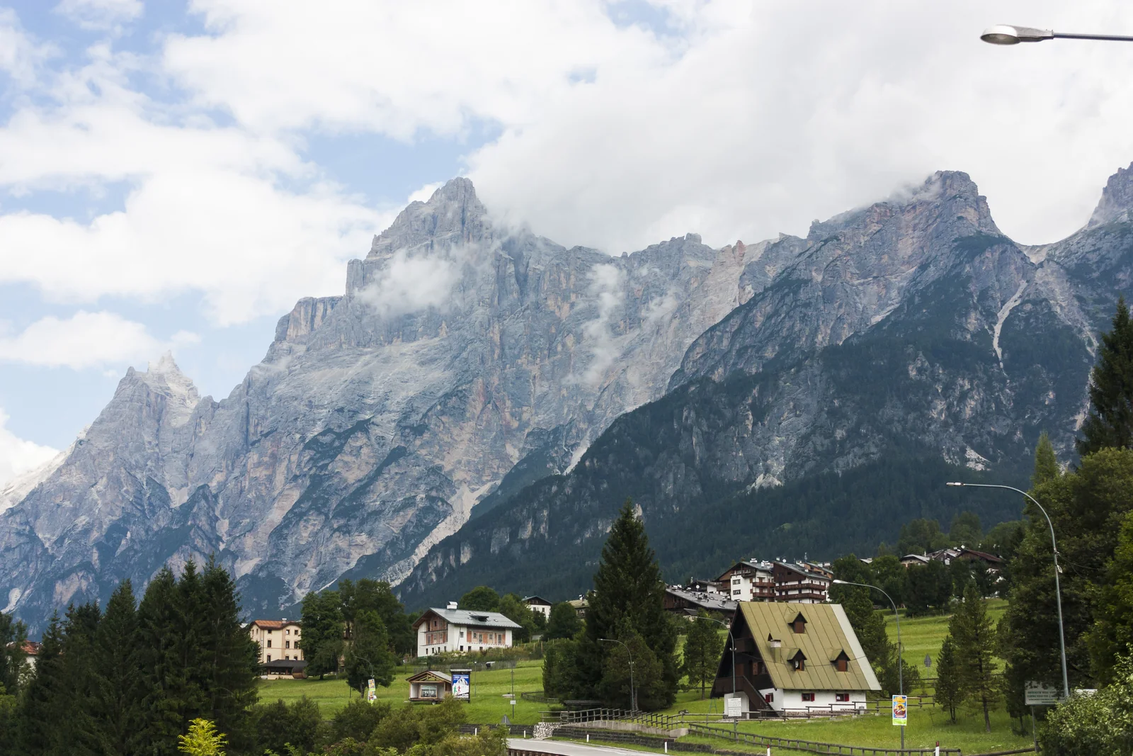 Cumbres rocosas de las Dolomitas sobre casas y prados de Cortina d’Ampezzo
