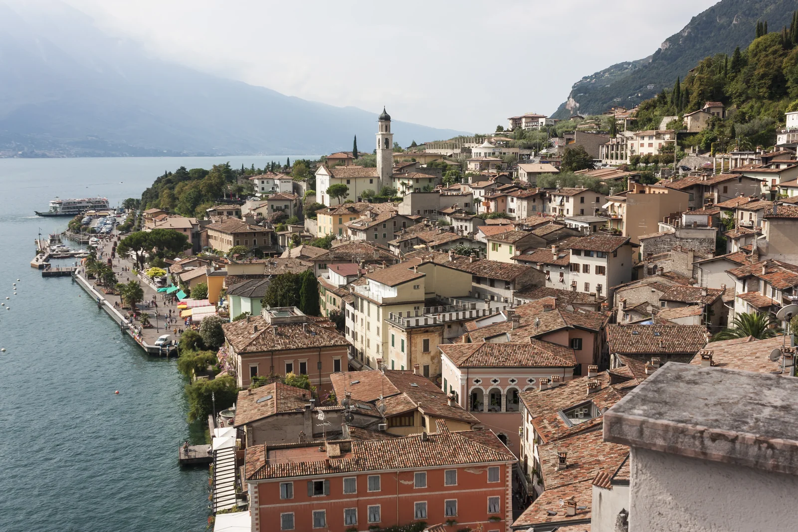 Casas de tejas rojizas en la orilla del lago de Garda, entre montañas