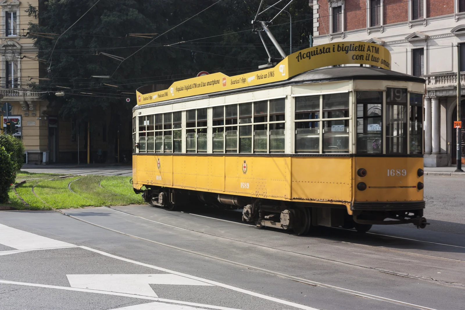 Tranvía amarillo de Milán entre árboles y edificios de la ciudad