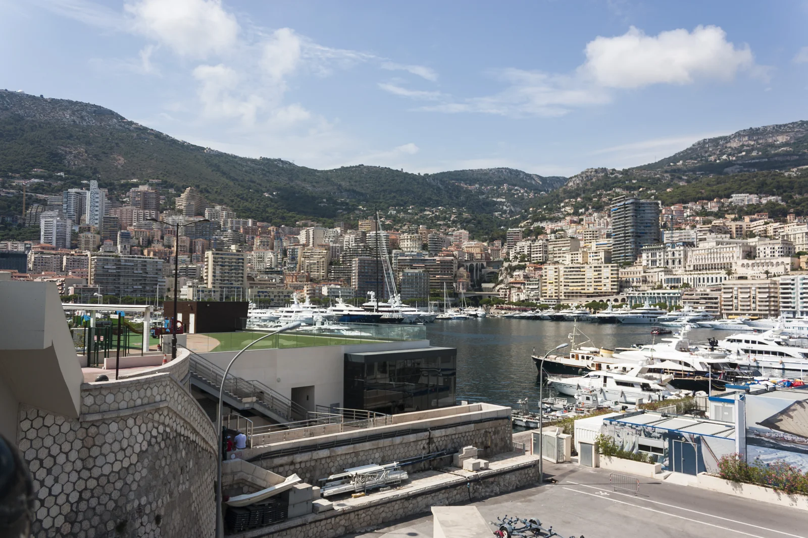 Puerto de Mónaco con yates, edificios y montañas al fondo